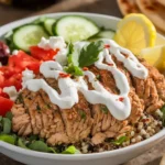 Mediterranean ground chicken bowl with juicy spiced chicken, fresh cucumber, cherry tomatoes, red onion, quinoa, and a dollop of tzatziki, garnished with parsley.
