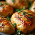 Close-up of garlic butter chicken hearts cooking in a skillet, garnished with fresh herbs.